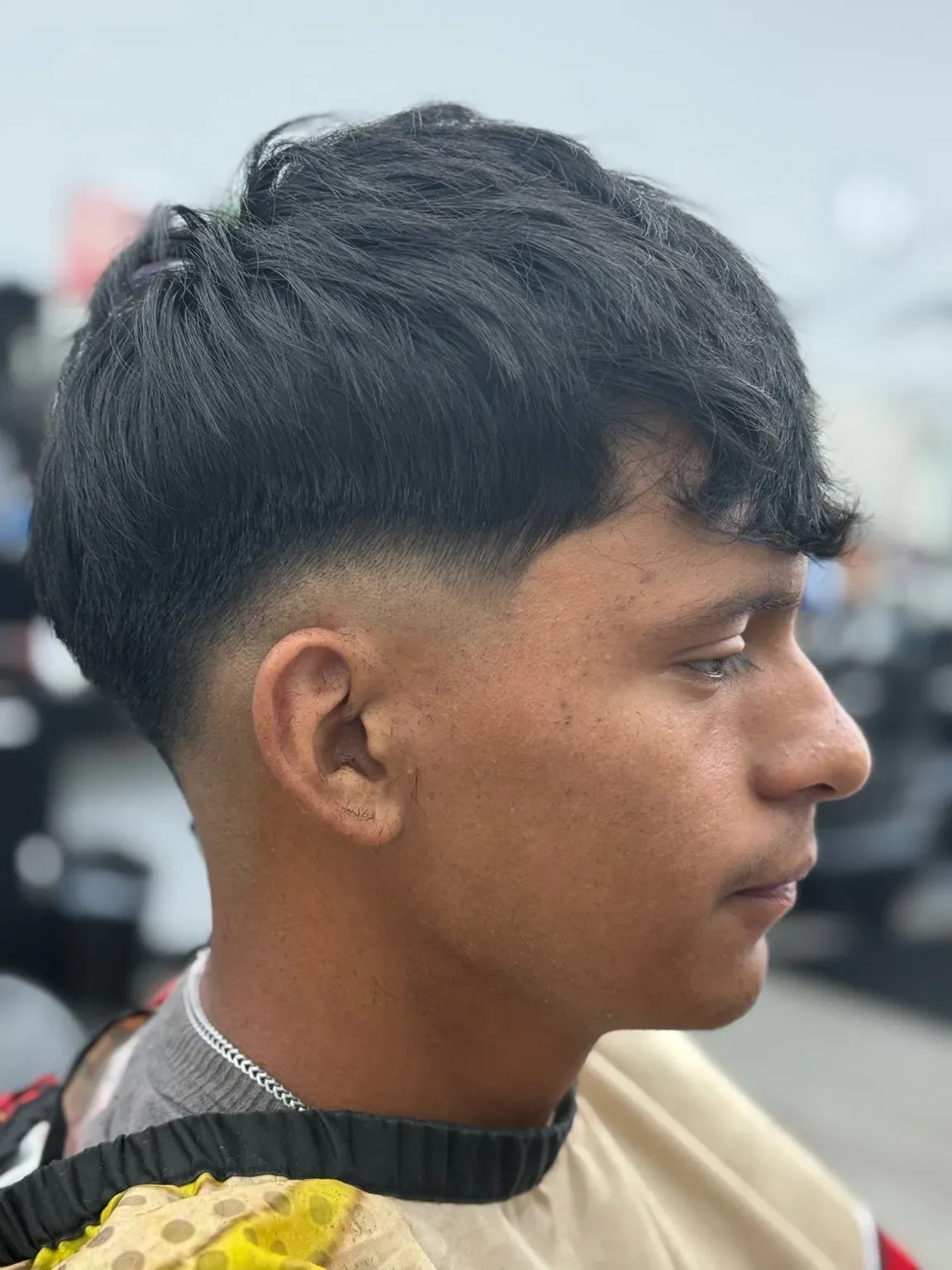 Man with dark hair and a fade haircut, posed in profile.