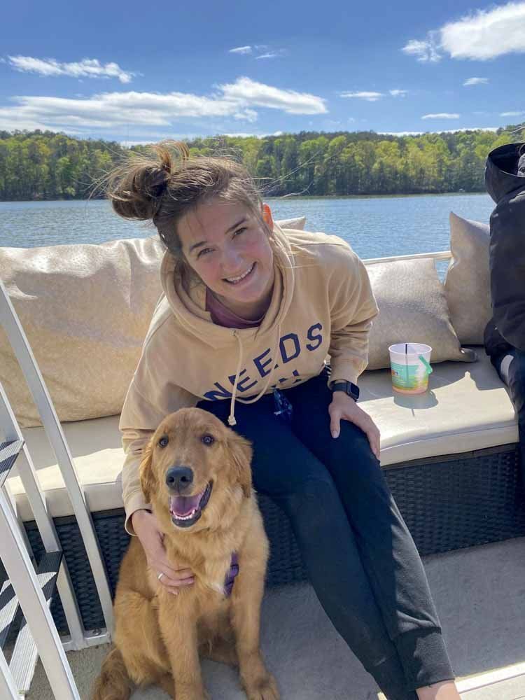 A woman is sitting on a boat with a dog.