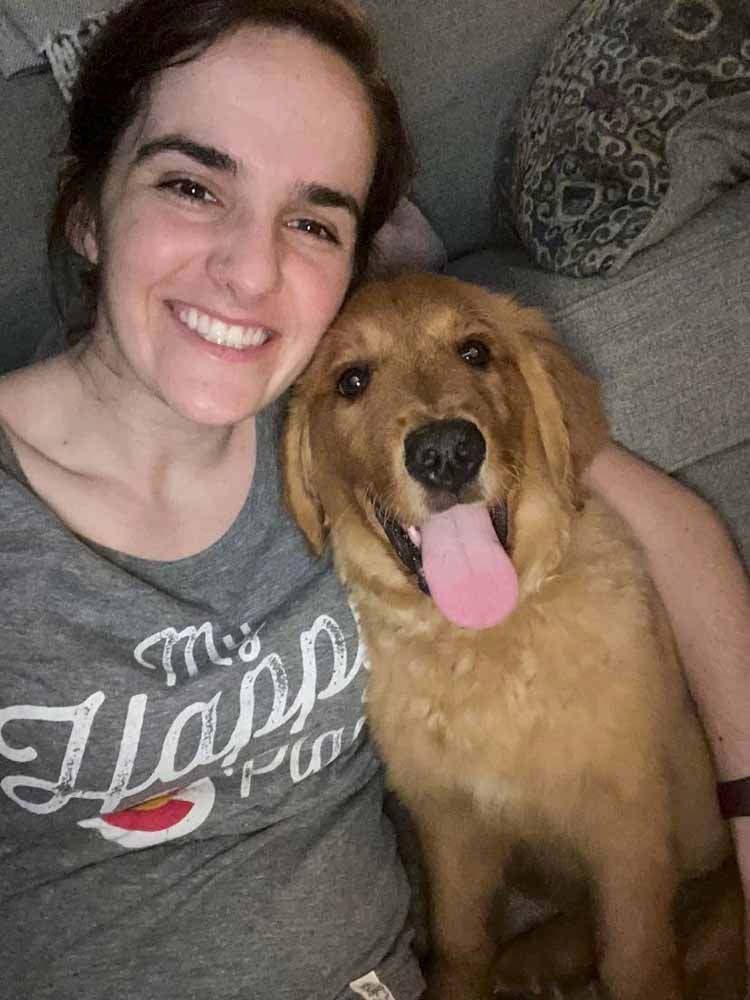 A woman is sitting on a couch holding a dog.