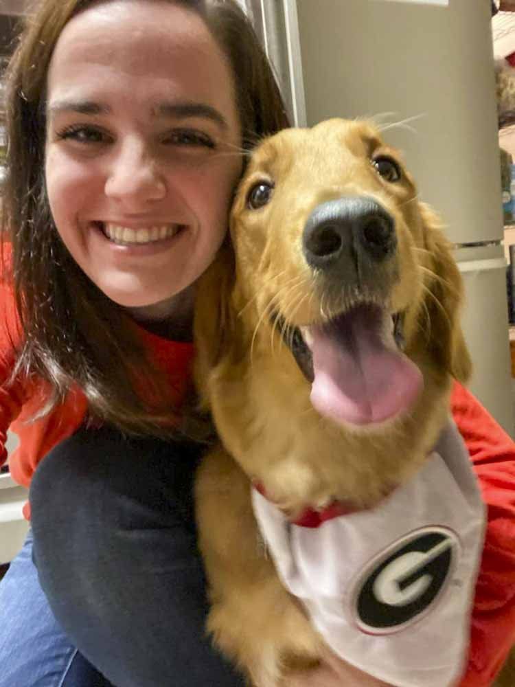 A woman is holding a dog wearing a georgia jersey.