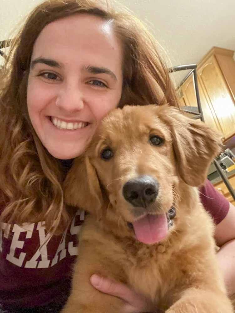 A woman is holding a puppy in her arms and smiling.