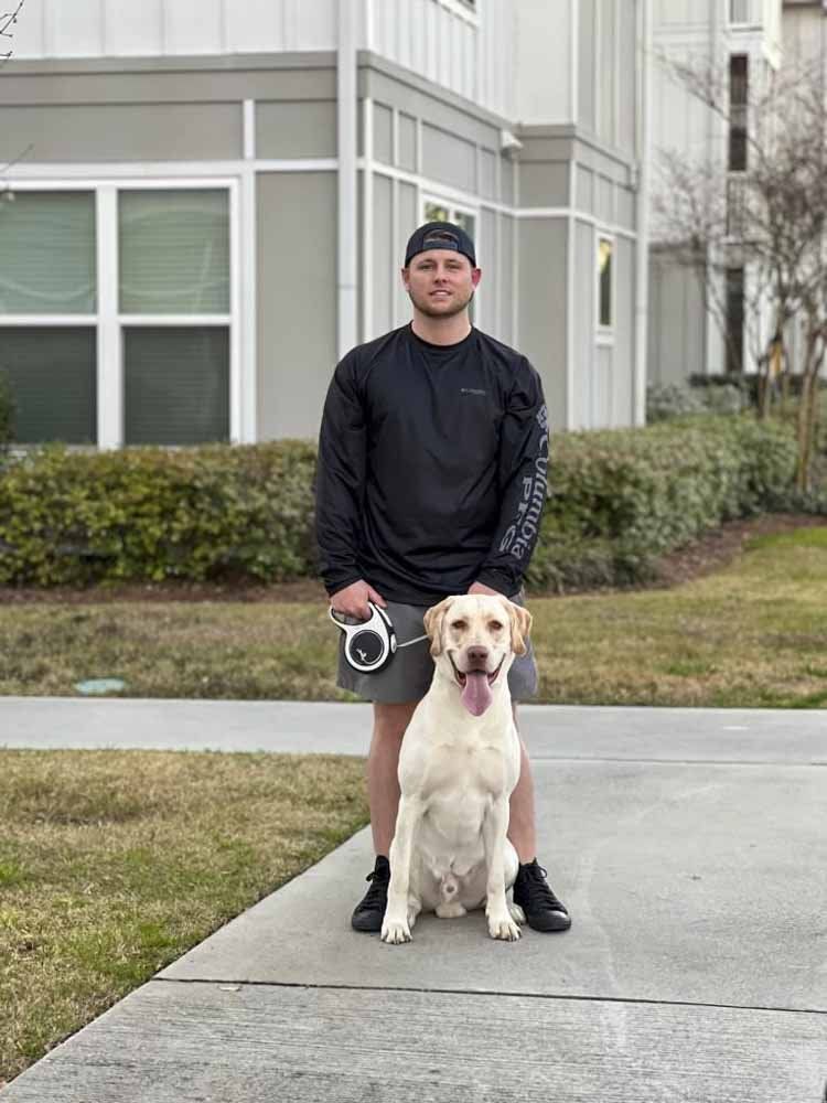 A man is standing next to a dog on a sidewalk.