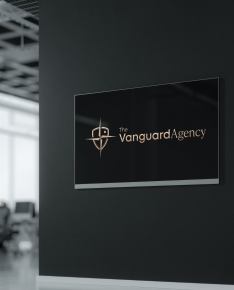 Black sign on black wall: “The Vanguard Agency” logo, white text within a white-lined rectangle.