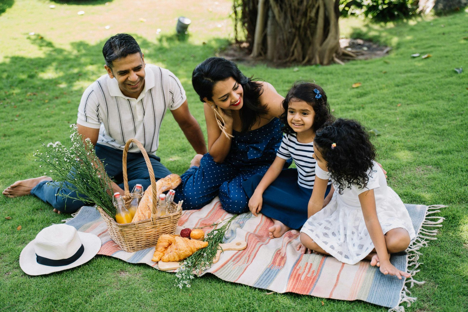 A family of four having a picnic at a park.