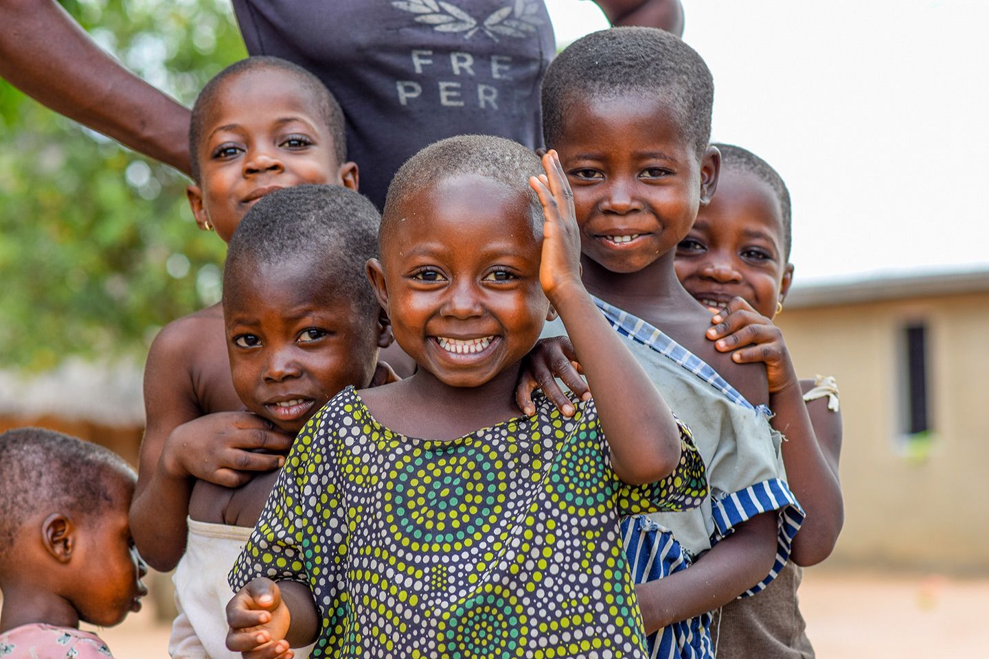 Group of children smiling and looking at the camera outdoors.