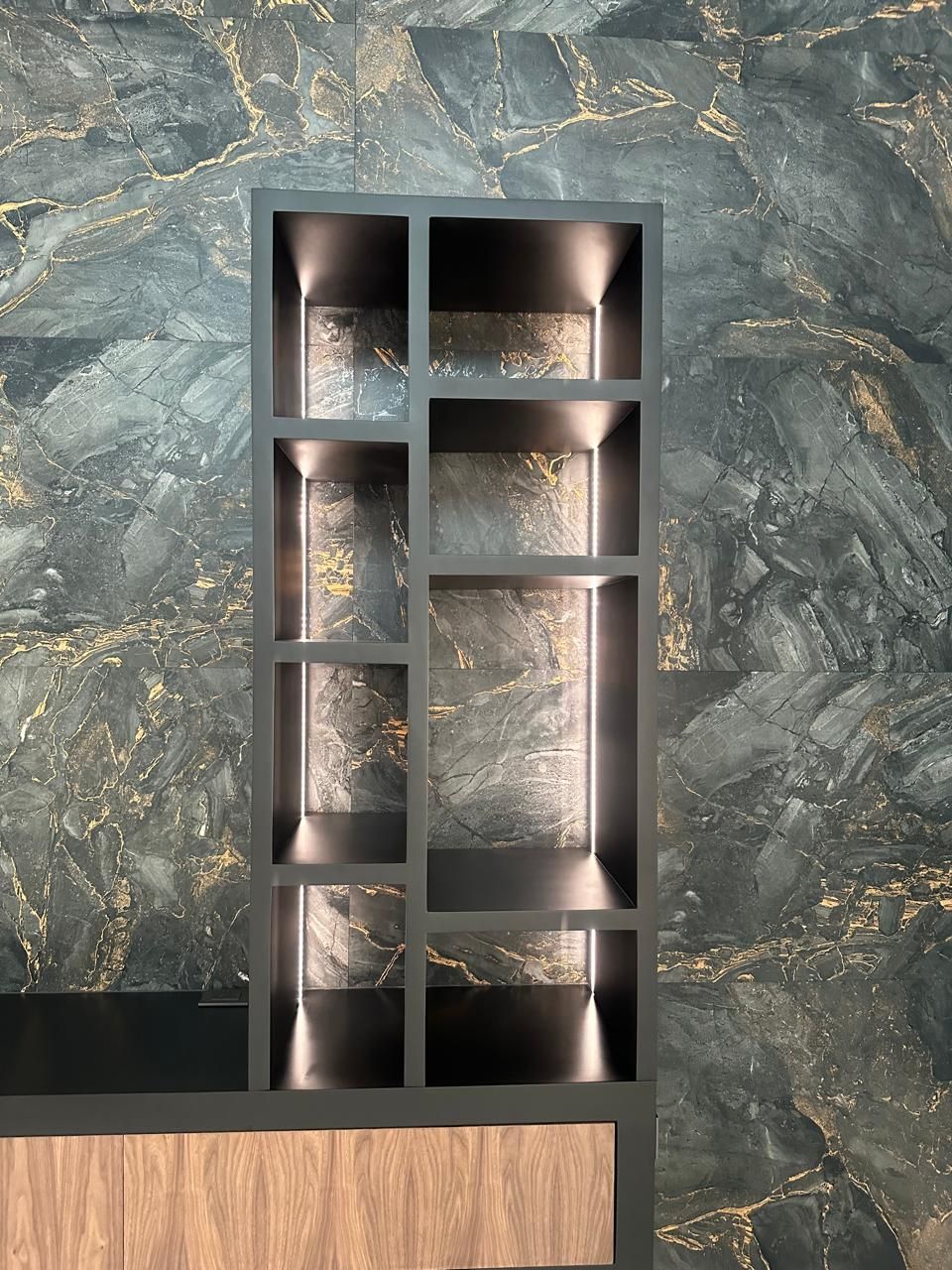 Estantería rectangular negra empotrada en pared con acabado texturizado en gris oscuro y dorado.