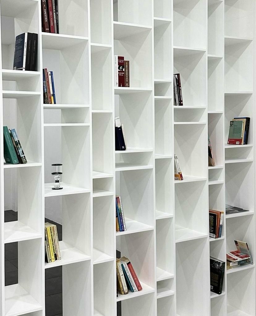 Estanterías blancas llenas de libros, dispuestos en forma de cuadrícula.