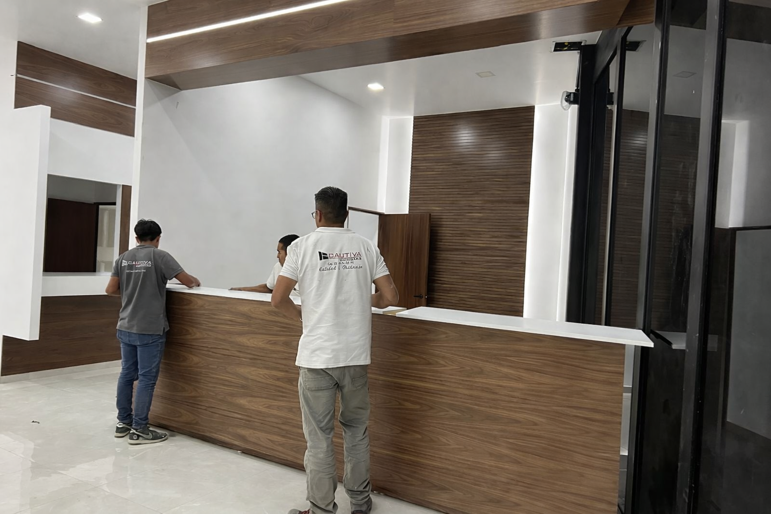 Obreros instalando paneles de madera en un edificio. Uno usa una escalera, otros se suben a un andamio.