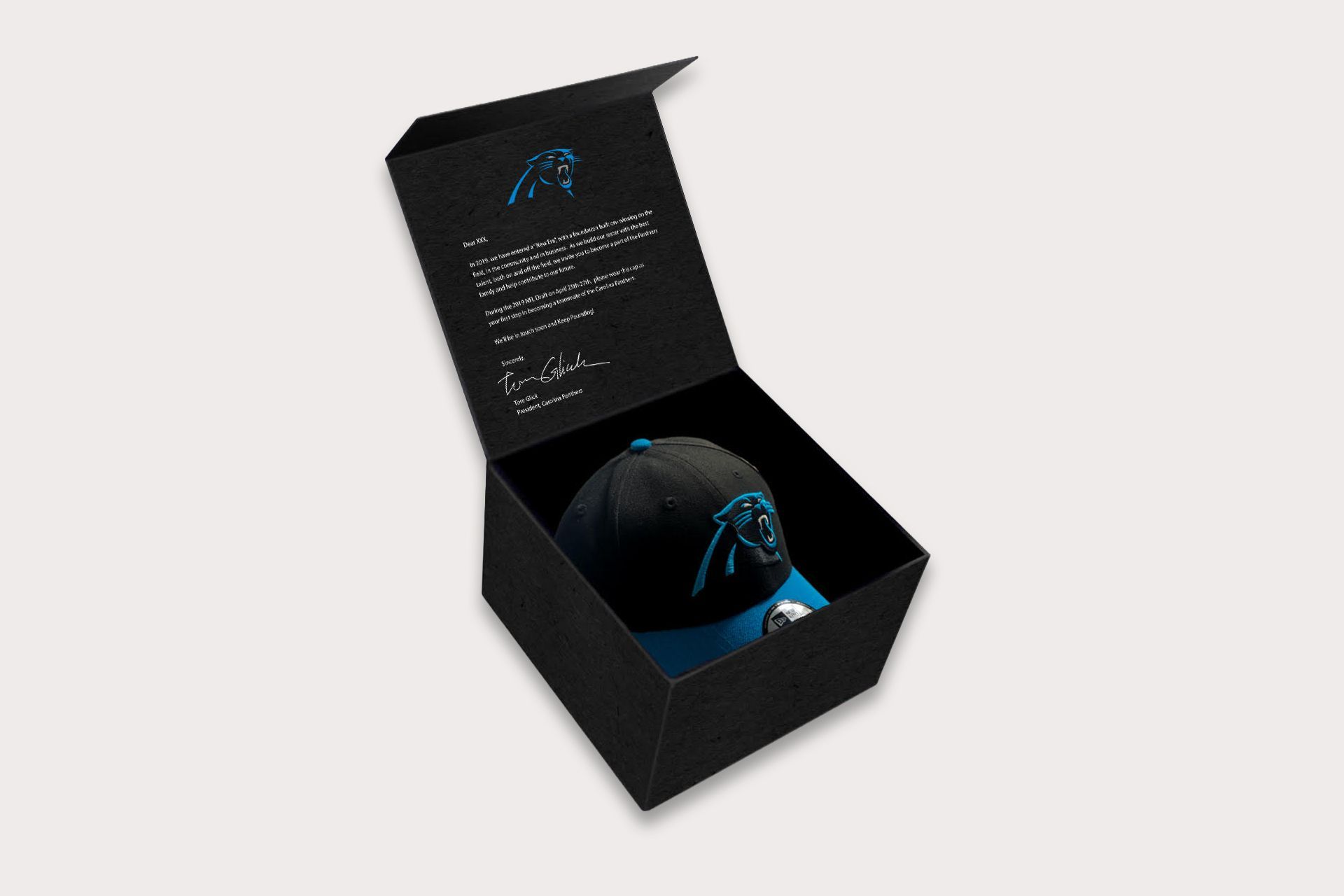Black box open, Carolina Panthers hat inside, text and logo on the lid.
