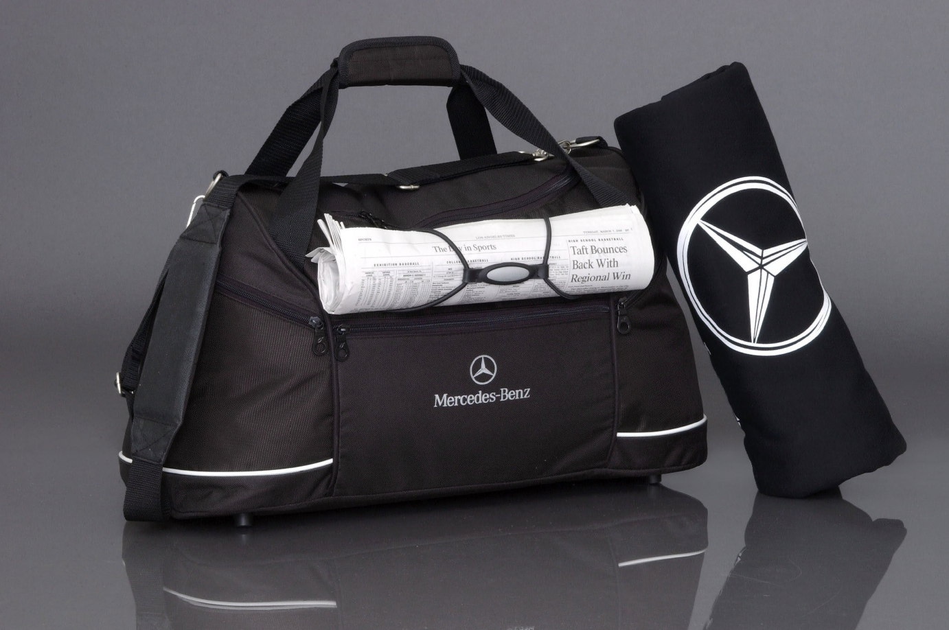Black Mercedes-Benz gym bag with white trim and logo, next to a black yoga mat with Mercedes logo.