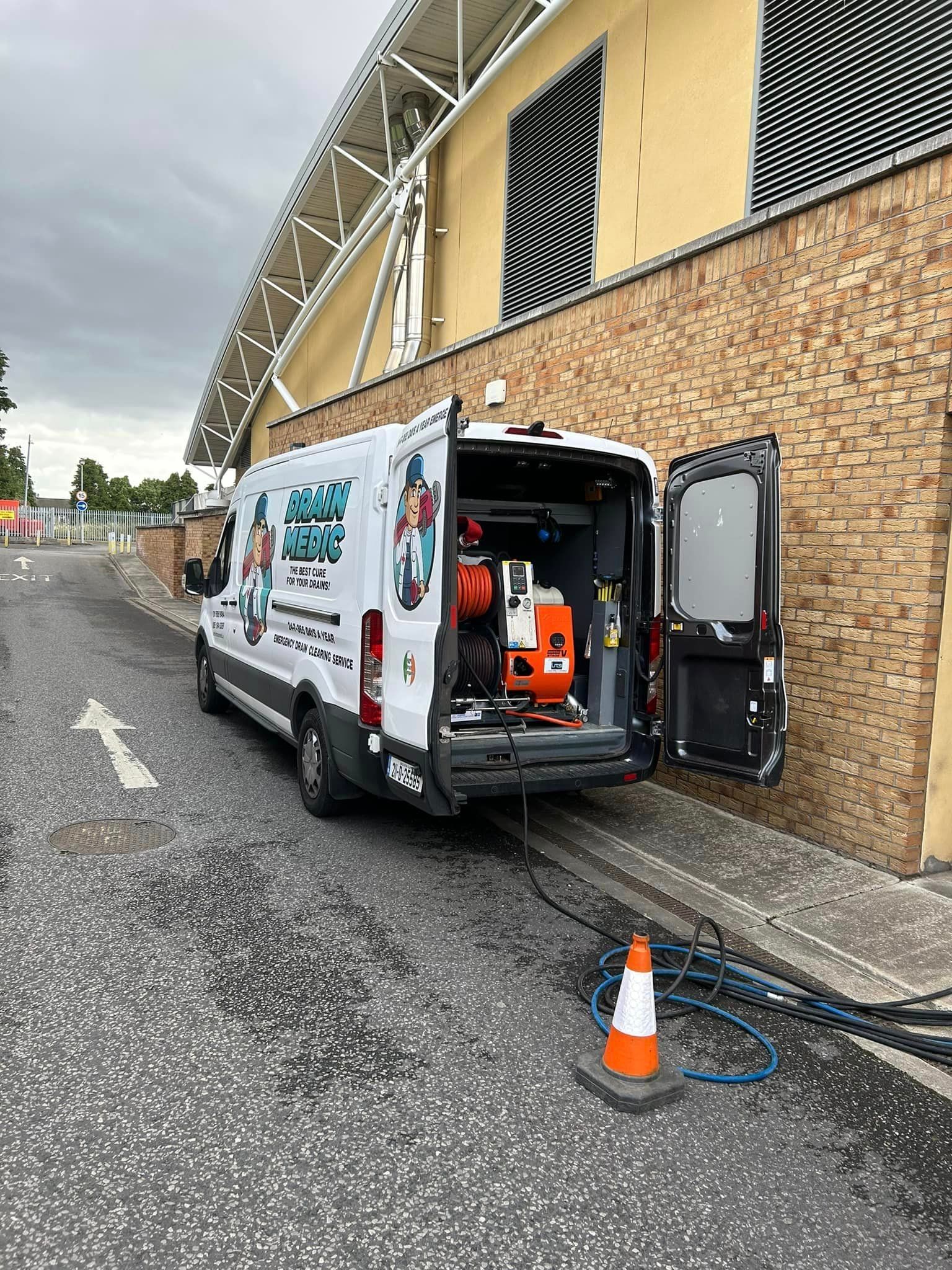 A white van is parked on the side of the road in front of a building.