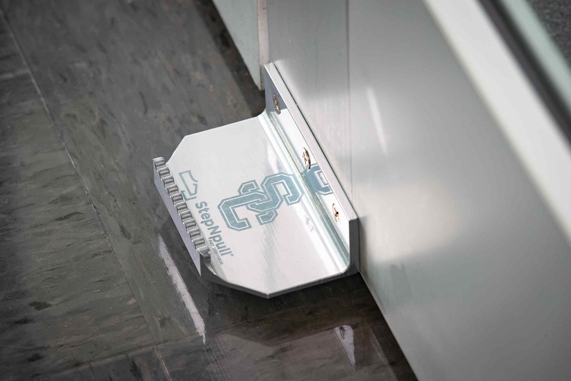 A metal foot rest is sitting on the floor next to a door.