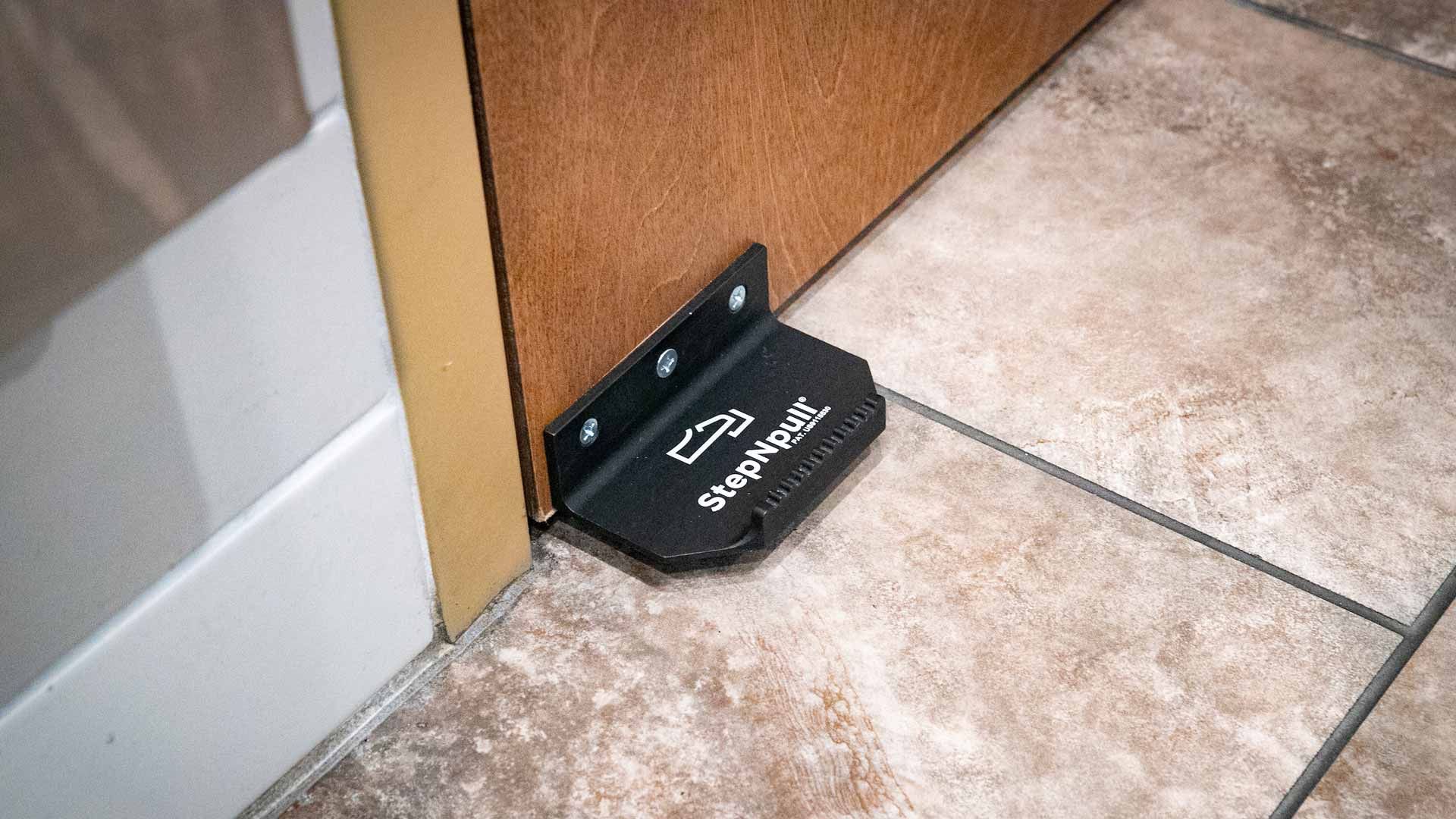 A door stop is sitting on a tiled floor next to a door.