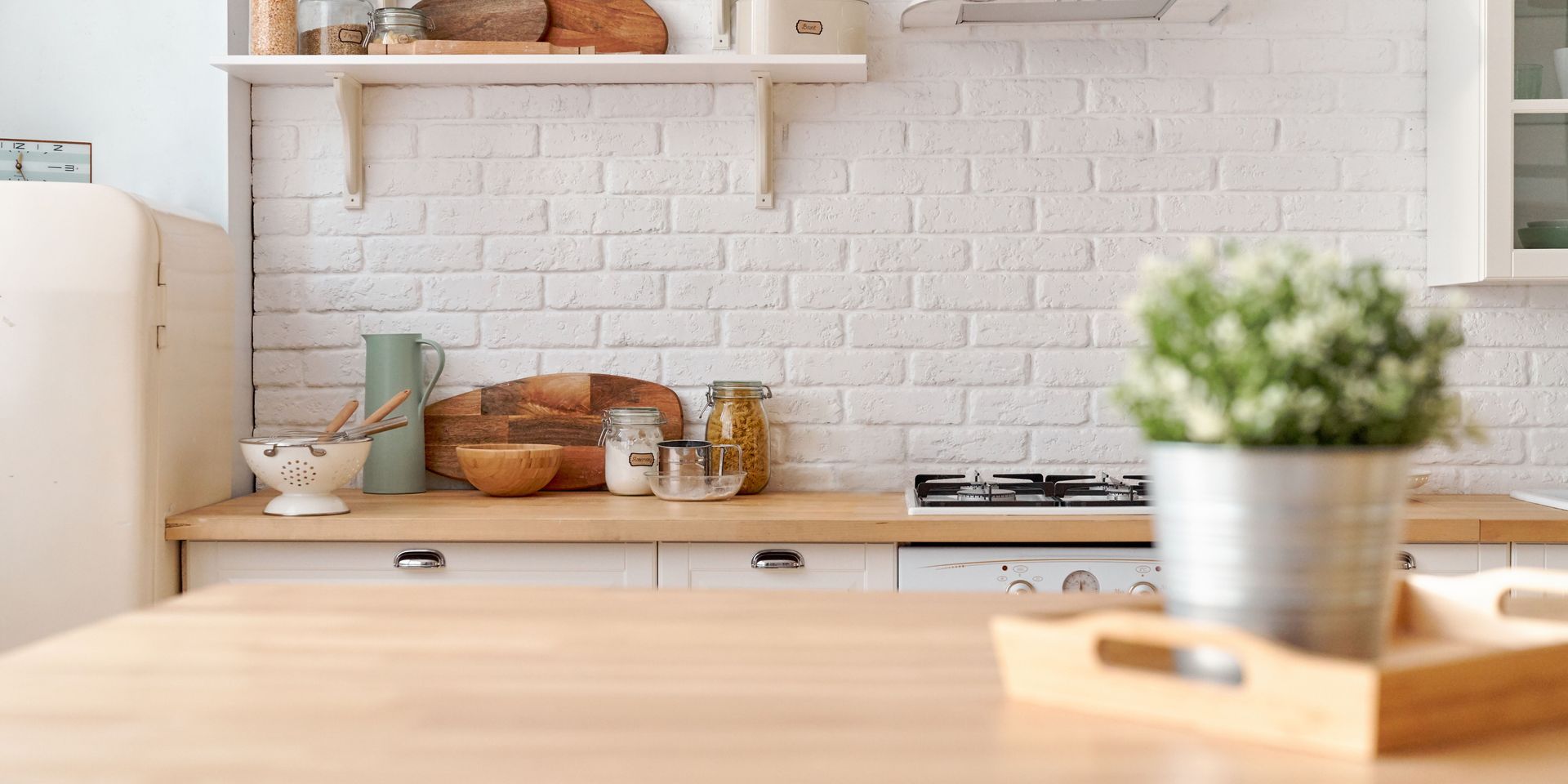 Cozy kitchen with a wooden countertop, white brick wall, and a potted plant.