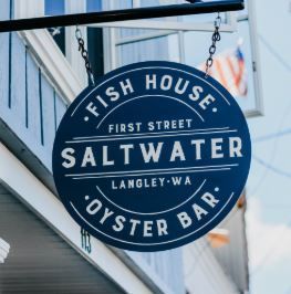 A blue sign that says fish house first street saltwater oyster bar