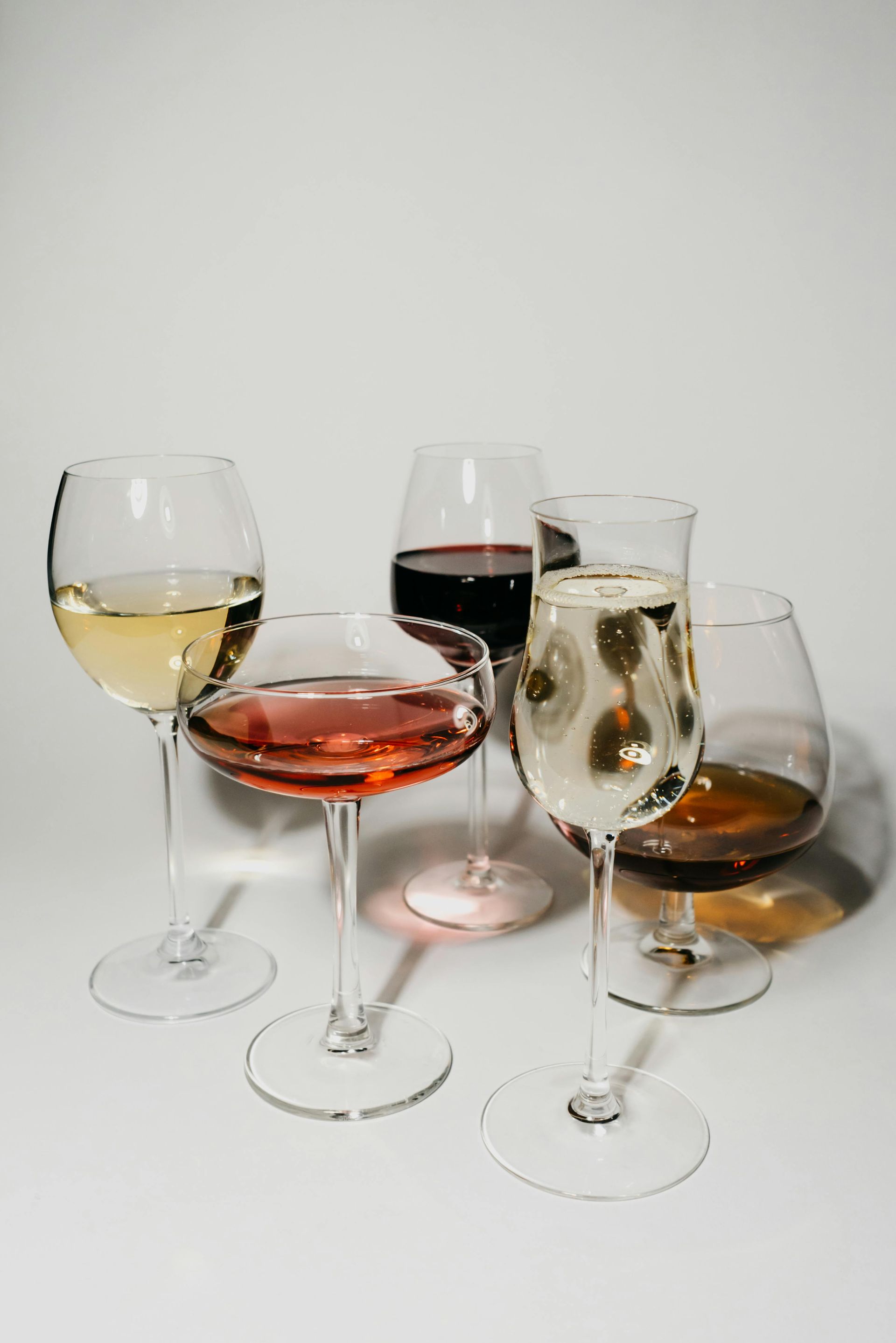 A group of wine glasses filled with different types of wine.