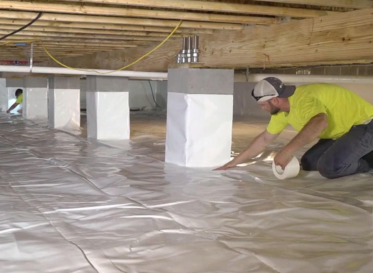 A man is kneeling on the floor of a basement.