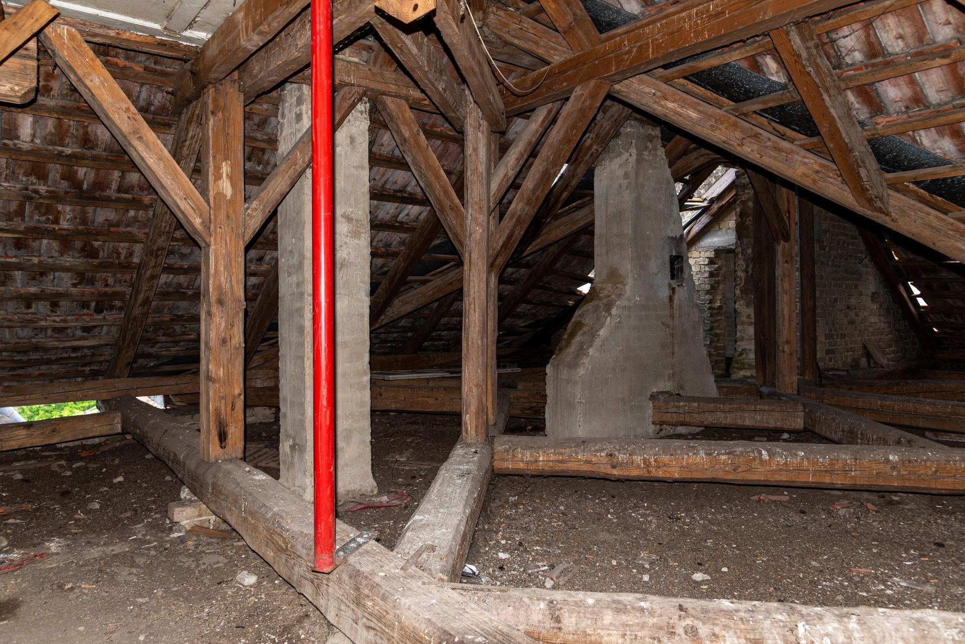 There is a red pole in the attic of a building.