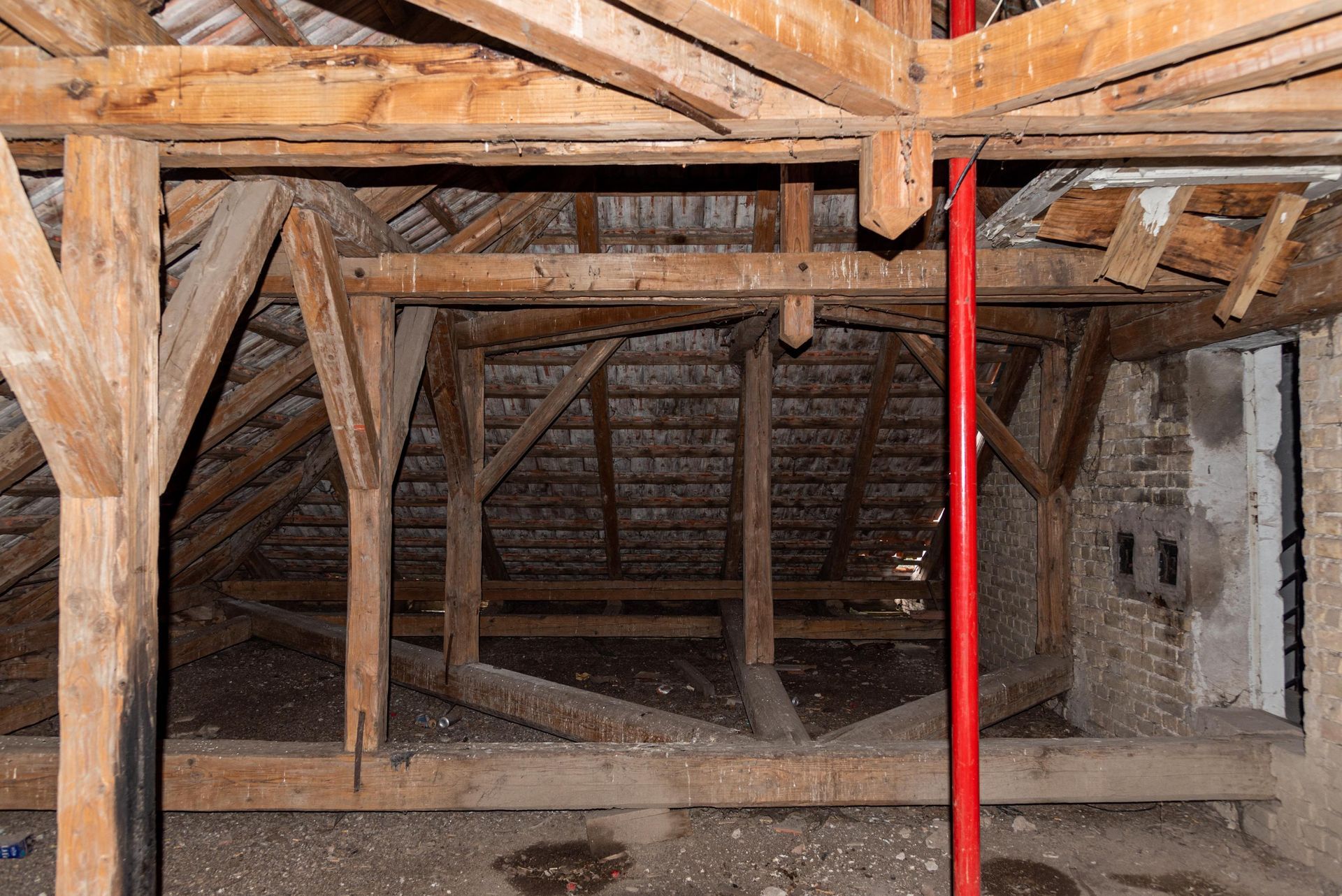 The inside of a building with wooden beams and a red pole.