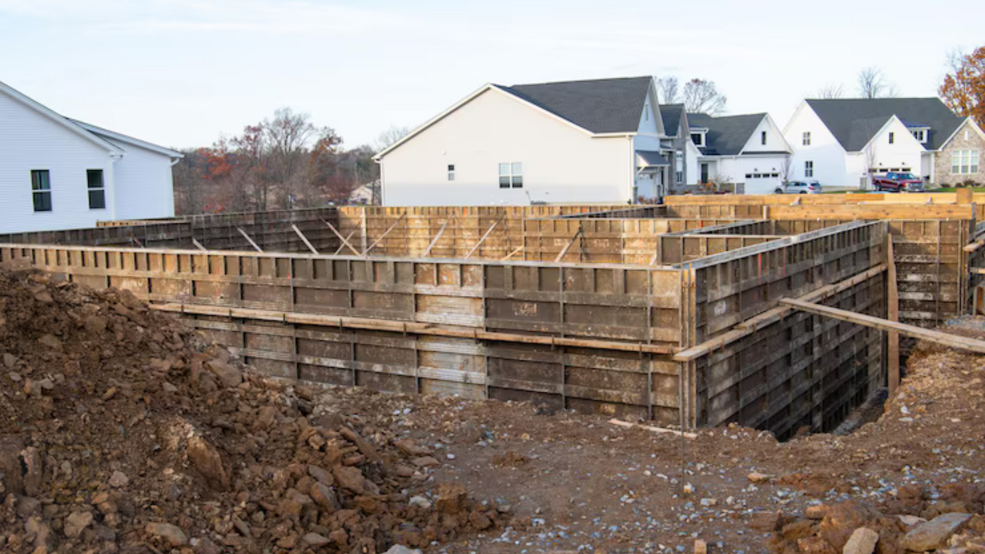 A large pile of dirt is sitting in front of a house under construction.