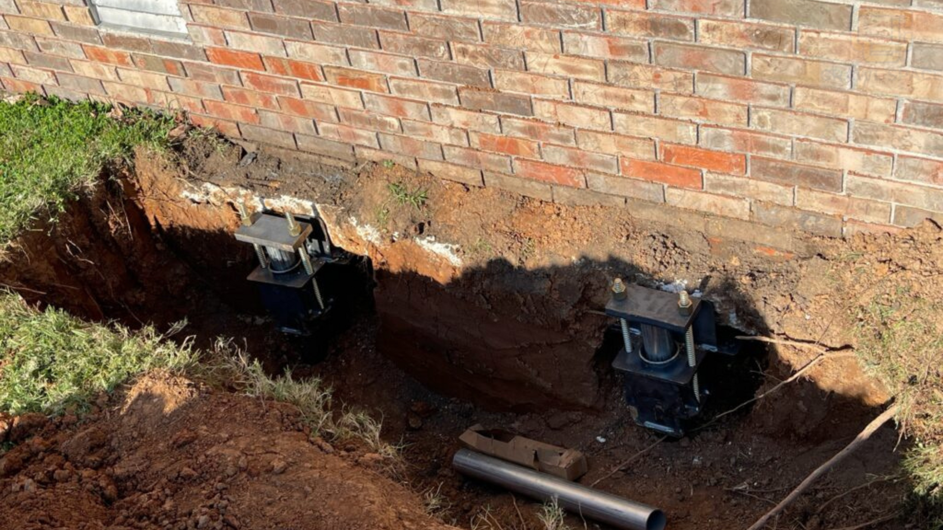 A brick wall with a hole in the ground in front of it.