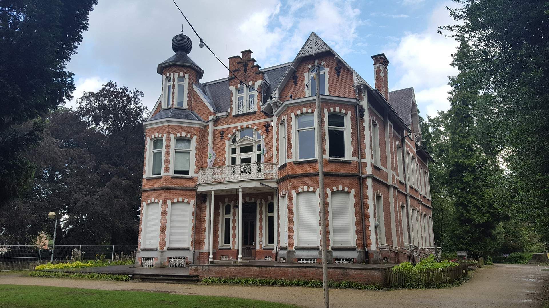 A large brick building with a lot of windows is surrounded by trees.