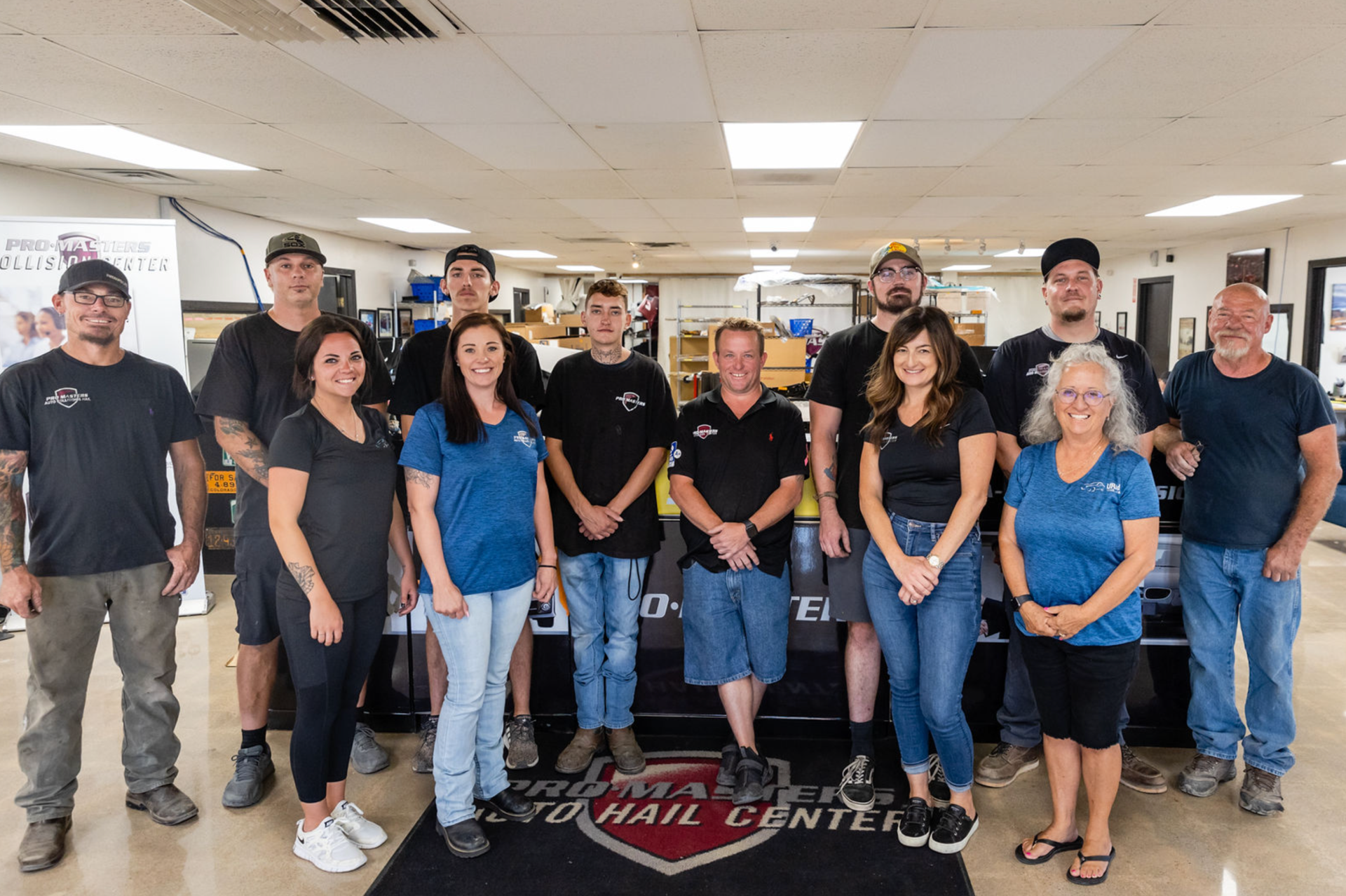 Group of people posing together inside an auto hail repair center.