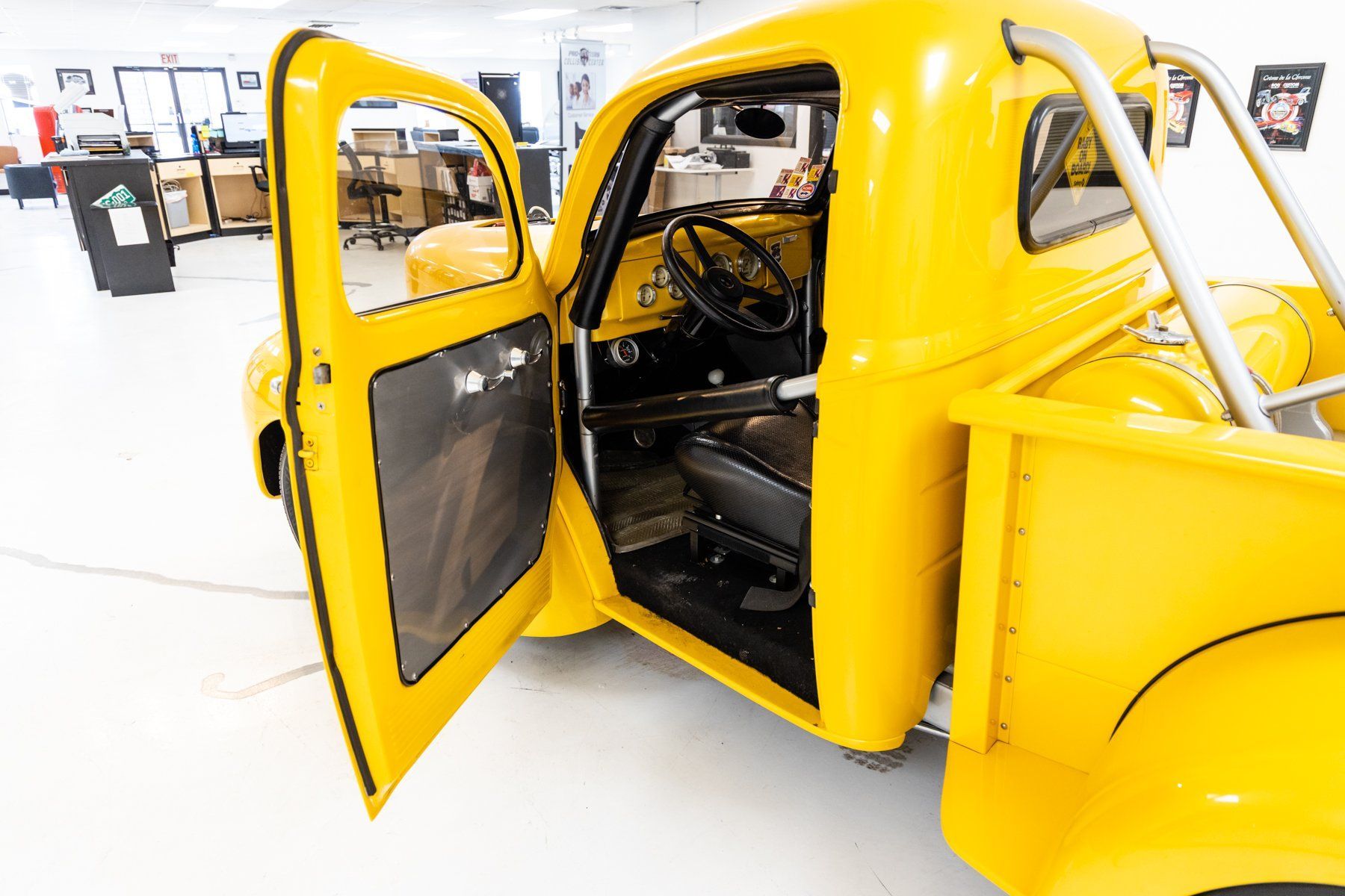 Bright yellow vintage pickup truck with the door open, showing the interior.