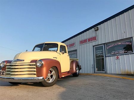 Tan and copper Chevrolet pickup truck parked outside a shop labeled