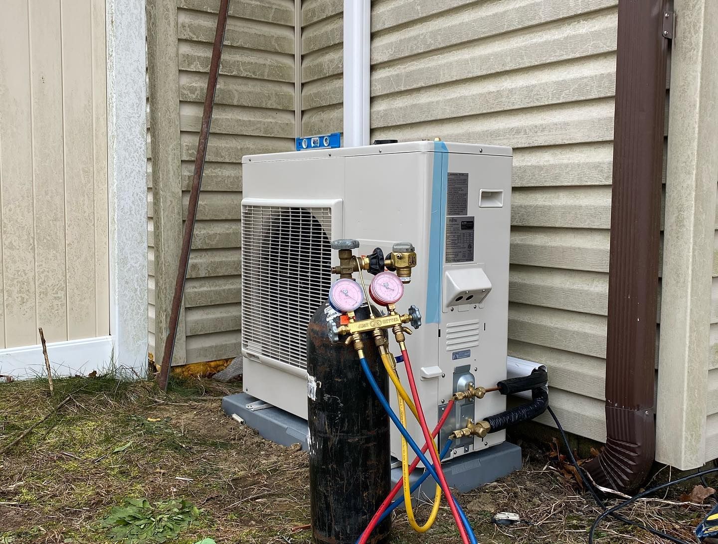 An air conditioner is being installed on the side of a house.