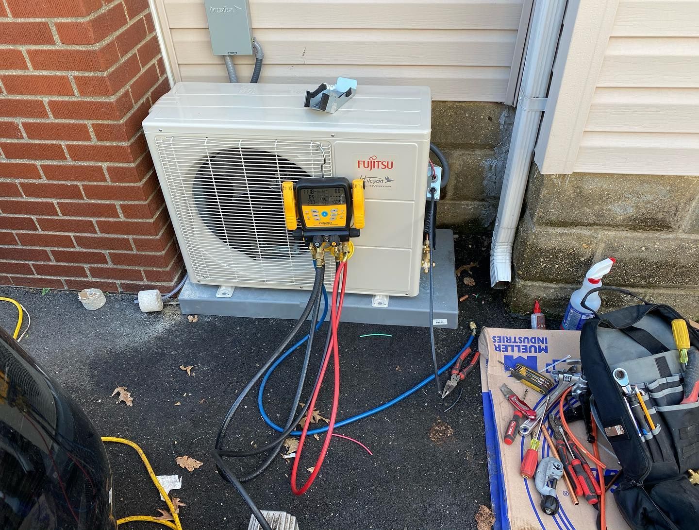 An air conditioner is being installed on the side of a brick building.
