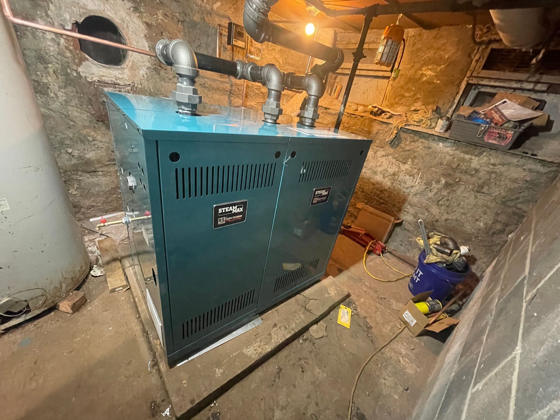 A blue boiler is sitting in a basement next to a water heater.