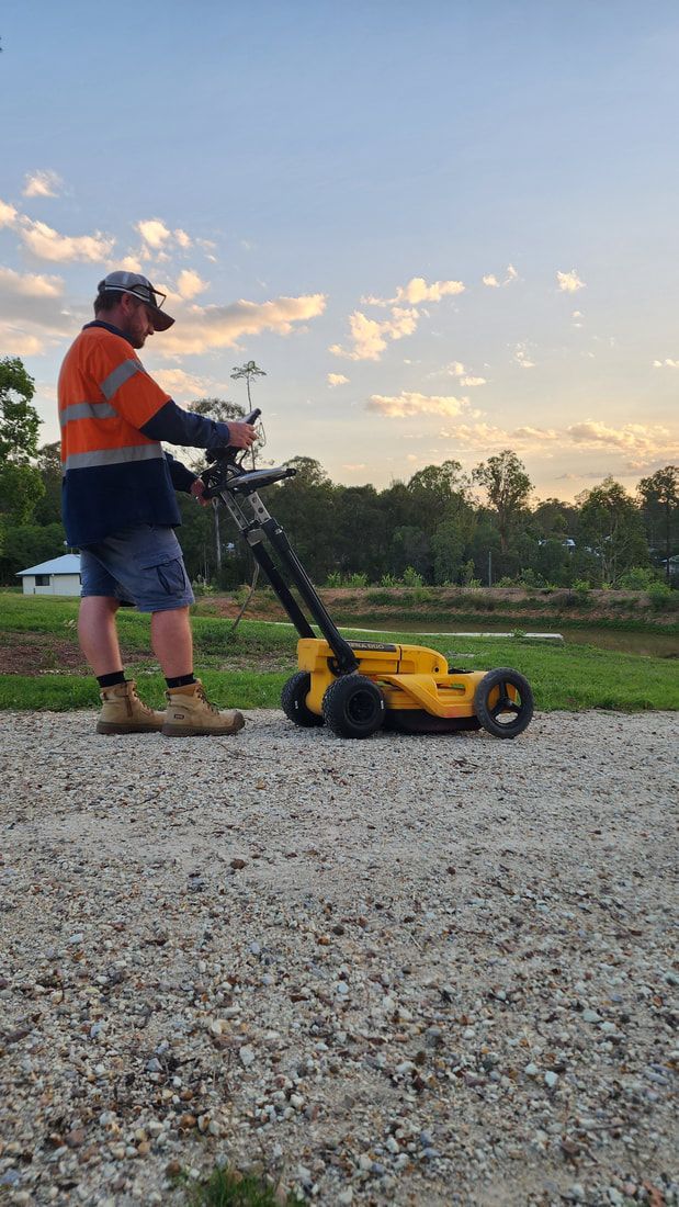 Man in Work Clothes Mowing Gravel Path With a Yellow Machine Against a Sunset Backdrop — Found It Down Under in Gympie, QLD