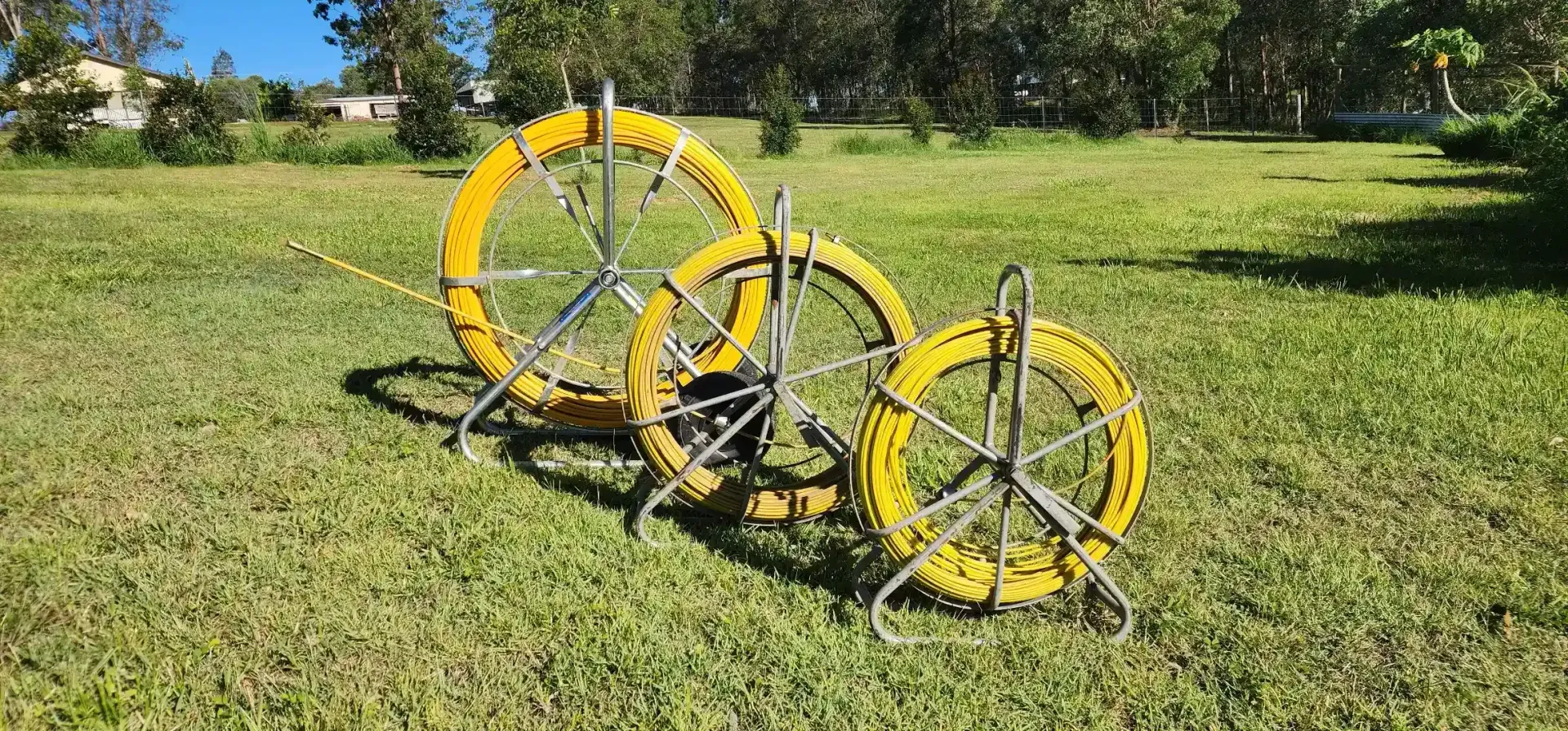 Three yellow cable reels on a grassy field with trees in the background under a blue sky. — Found It Down Under in Gympie, QLD