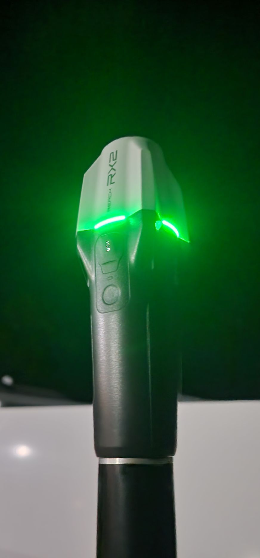 A black and silver device with a green laser emitting light, in a green lit environment.