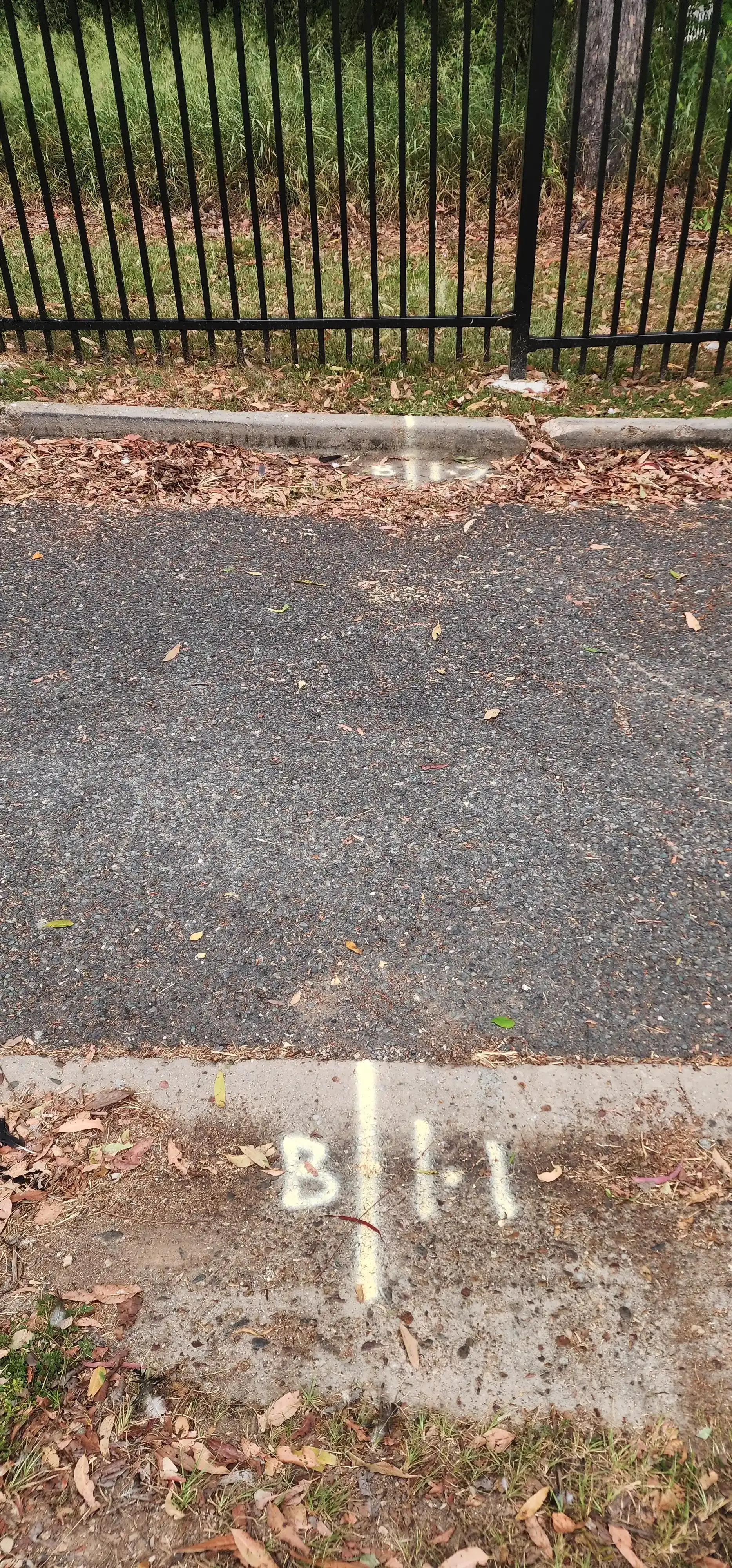 Asphalt road with markings “B I1” and a metal fence in the background. — Found It Down Under in Gympie, QLD