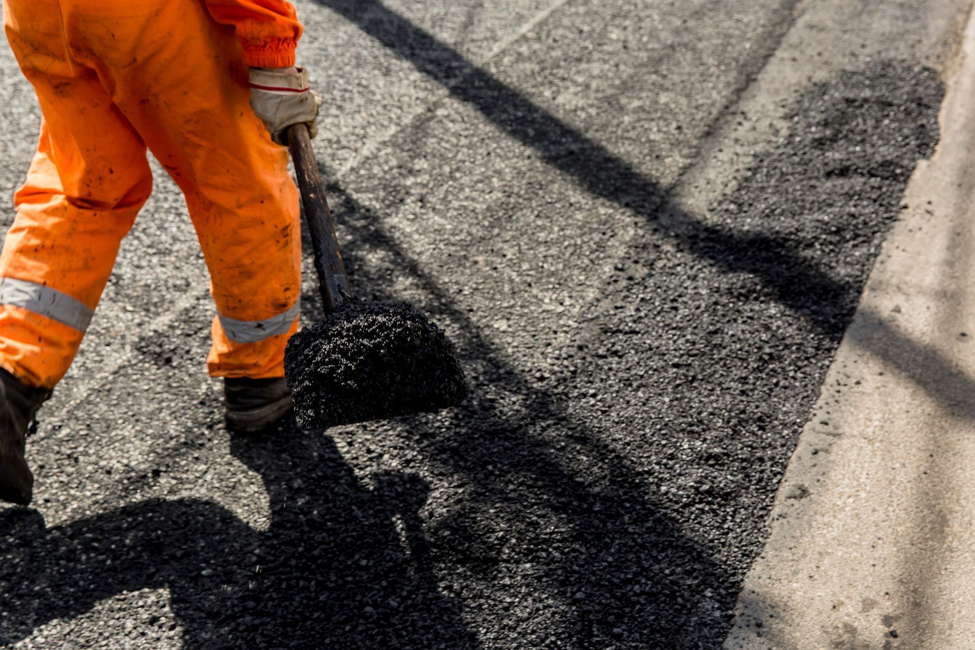 A worker spreading hot asphalt on a road surface.
