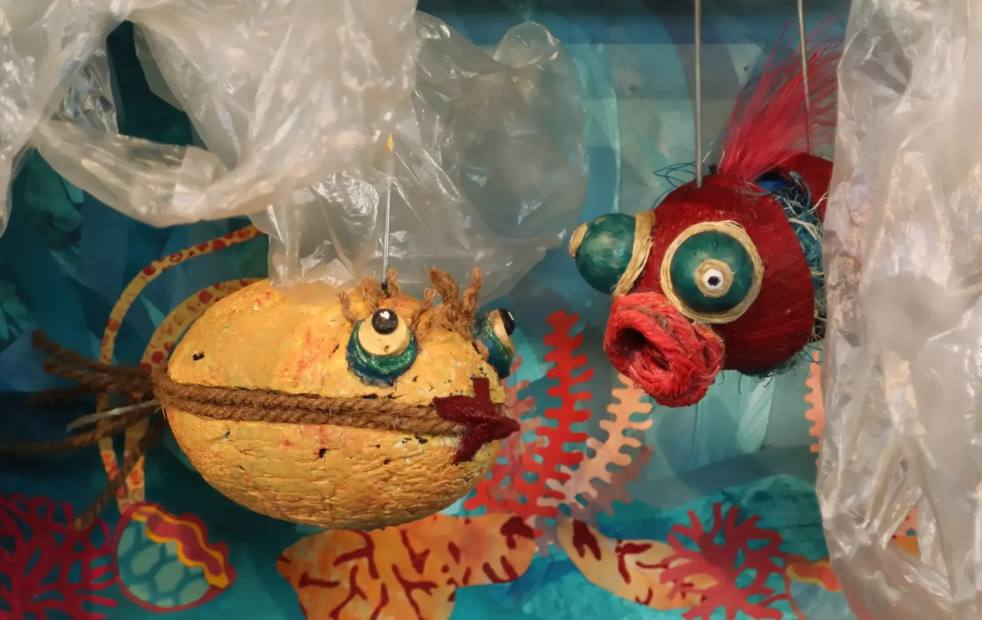 Ein gelber und ein roter Fisch hängen an einer Plastiktüte