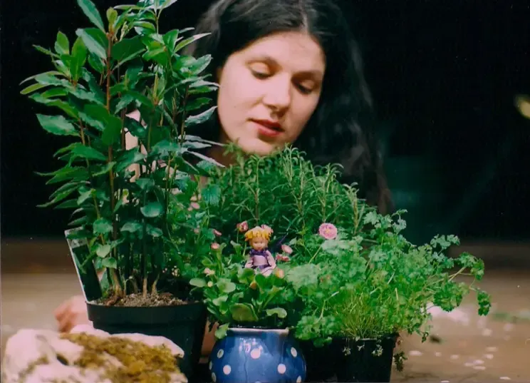 Eine Frau betrachtet eine Topfpflanze mit einer Puppe darin