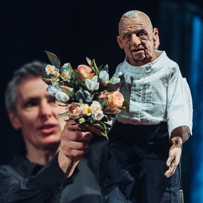 Ein Mann hält eine Puppe mit Blumen in seinen Händen.