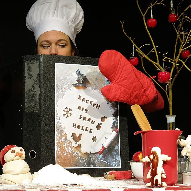 Eine Frau mit Kochmütze hält ein Buch mit dem Titel „Backen mit Frau Holle“ in der Hand