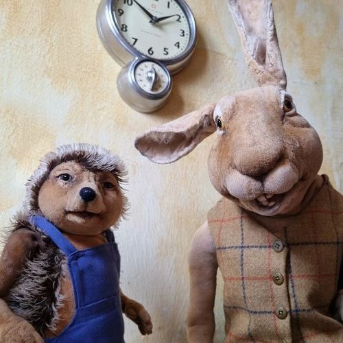 Ein ausgestopfter Igel und ein ausgestopfter Hase stehen vor einer Wanduhr