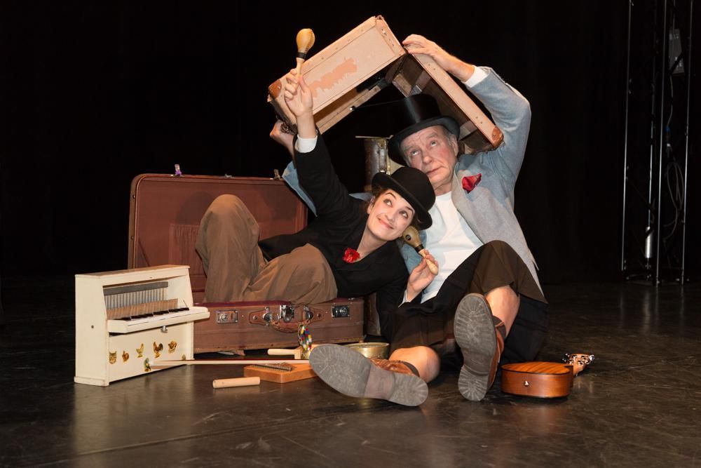 Ein Mann und eine Frau sitzen auf dem Boden, im Hintergrund ist ein Koffer zu sehen