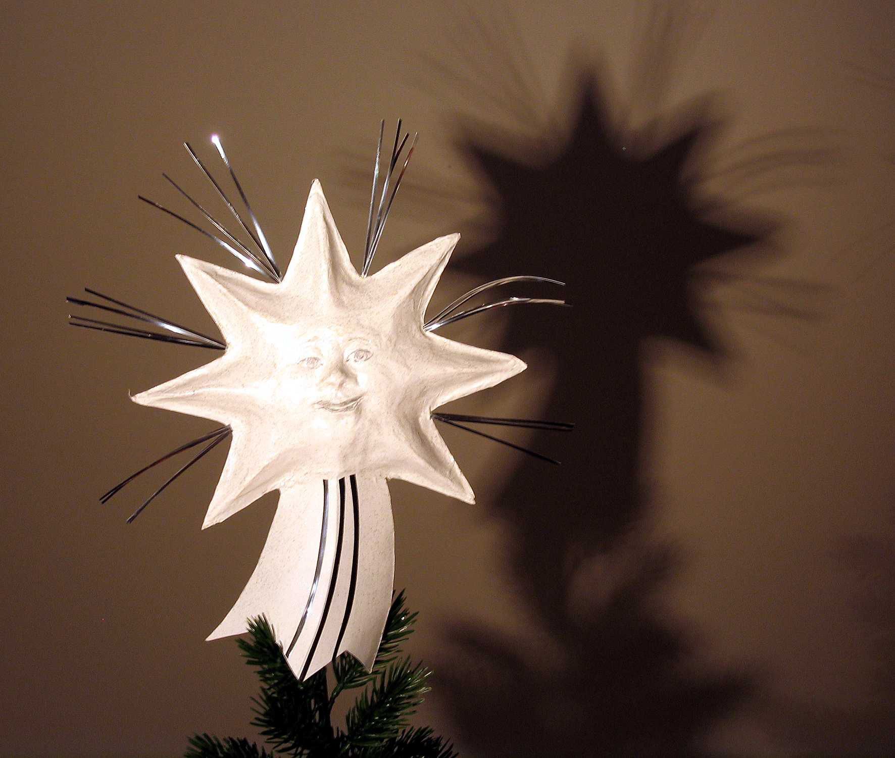 Ein weißer Stern mit einem Gesicht darauf ist auf der Spitze eines Weihnachtsbaumes