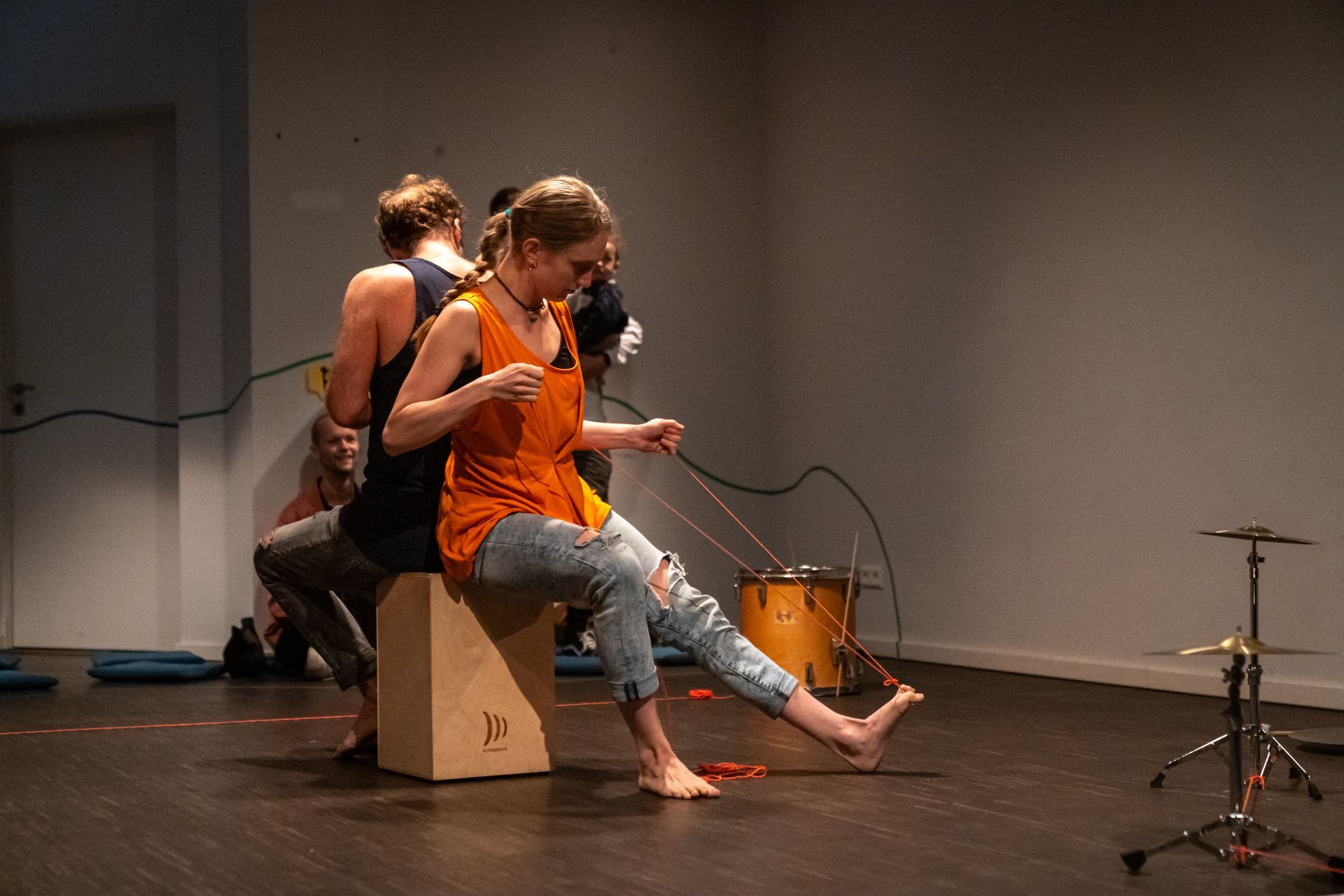 Eine Frau strickt und sitzt dabei auf einer Holzkiste mit dem Buchstaben K darauf