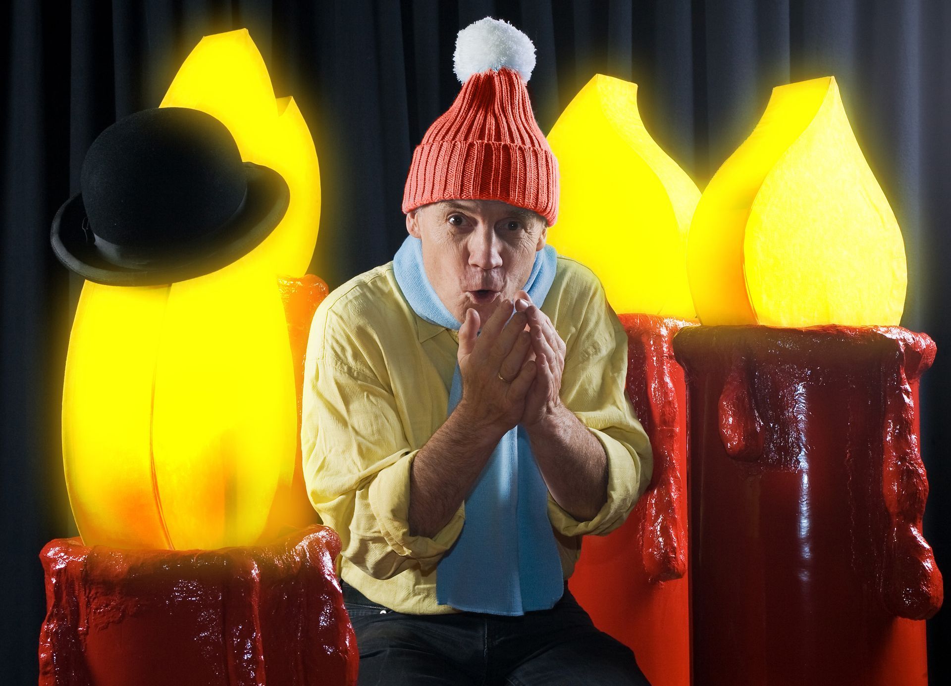 Ein Mann mit rotem Hut sitzt vor Kerzen