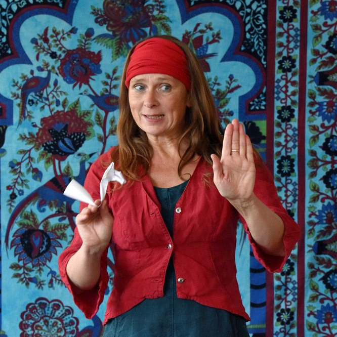 Eine Frau in einer roten Jacke trägt eine andere Frau auf ihrem Rücken.