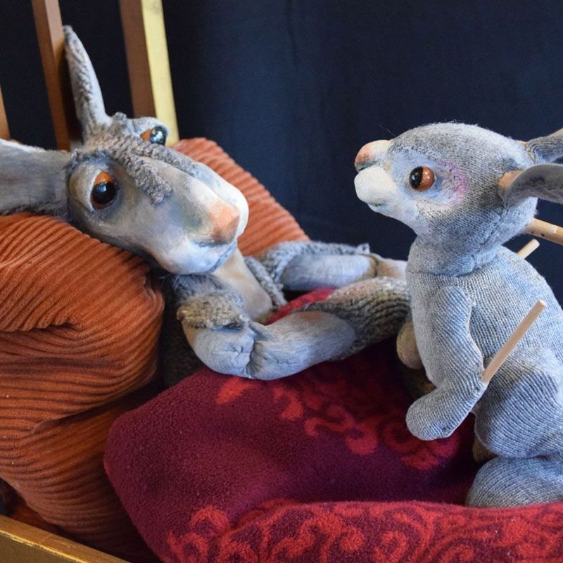 Ein Stoffkaninchen liegt auf einem Bett neben einem anderen Stoffkaninchen