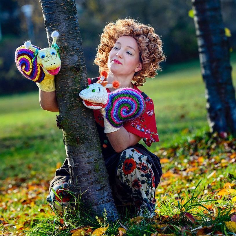 Eine Frau kniet neben einem Baum und hält eine Schneckenpuppe