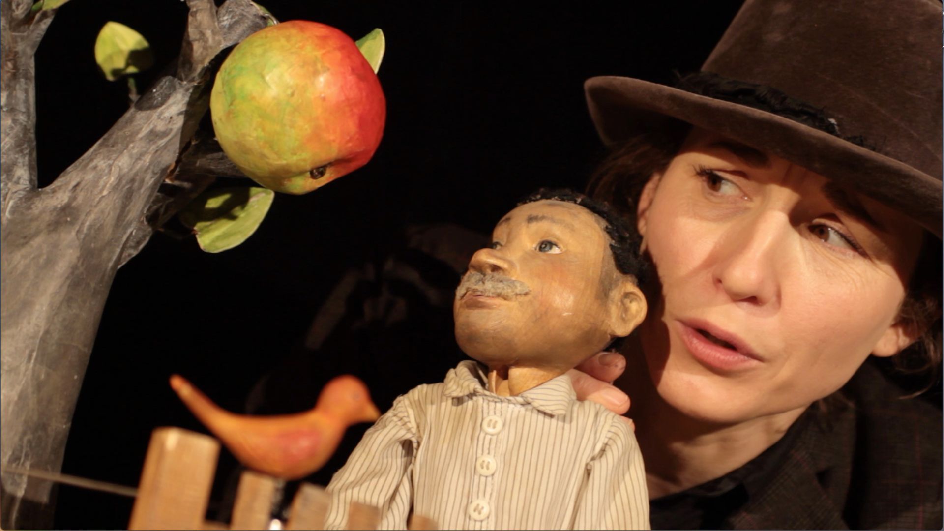 Eine Frau in einem lila Kleid sitzt mit ausgestreckten Armen unter einem Baum